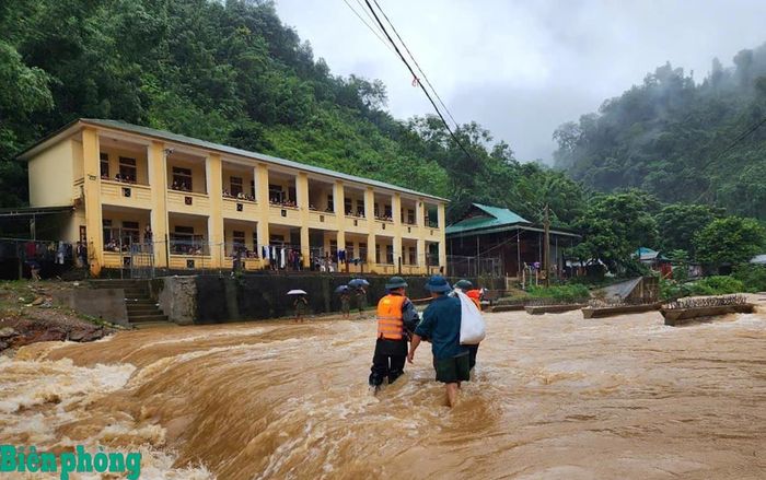 Cán bộ Đồn Biên phòng Tam Hợp và Ban Chỉ huy Quân sự xã Tam Thái vượt dòng nước lũ mang cơm đến cho học sinh trong thời gian giao thông bị chia cắt. Ảnh: Lê Thạch