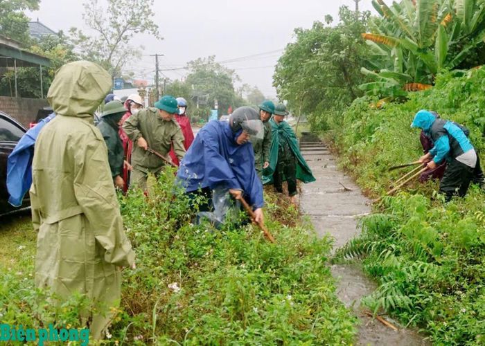 Cán bộ, chiến sĩ Đồn Biên phòng Hải Hòa phối hợp với các lực lượng và người dân khơi thông cống rãnh, giải phóng dòng chảy, hạn chế ngập úng do mưa lớn kéo dài. Ảnh: Hải Chuyền