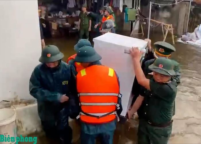 Cán bộ, chiến sĩ Đồn Biên phòng Sầm Sơn phối hợp với các lực lượng hỗ trợ người dân di chuyển tài sản ra khỏi khu vực ngập sâu, bảo đảm an toàn trong mưa lũ. Ảnh: Hải Chuyền