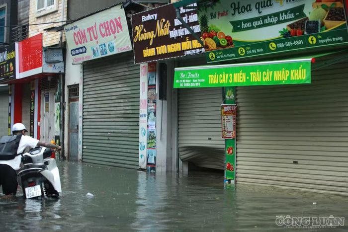 Nhiều phương tiện vận tải lớn đi qua khu vực ngập tạo sóng nước đánh mạnh vào các công trình, khiến cửa cuốn của một số hộ dân bị biến dạng.
