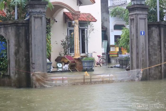 Nước ngập sát mép cửa nhiều nhà dân. Một số hộ phải be bờ, chăng lưới phía ngoài cổng nhằm hạn chế rác thải và vật dụng theo dòng nước trôi vào nhà.