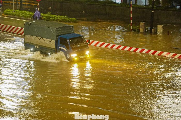 Một số tài xế vẫn cố điều khiển ô tô qua vùng nước sâu. Sóng nước do phương tiện tạo ra liên tục dồn về hai bên đường.