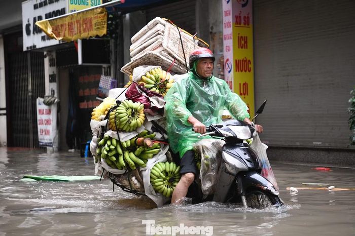 Dù nước ngập ngang xe máy, người chở hàng cố xoay xở để kịp giao chuyến sớm.