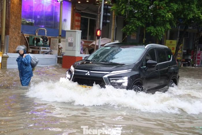 Ô tô chật vật di chuyển qua dòng nước ngập sâu trên đường Lê Trọng Tấn tại khu đô thị Geleximco.
