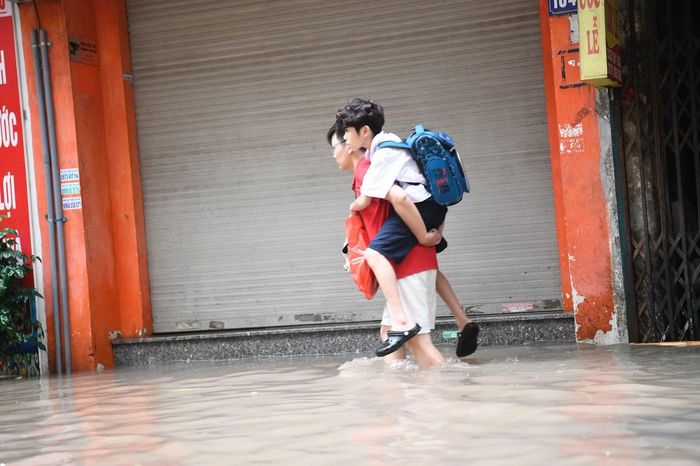 Một số tuyến đường bị ngập, phụ huynh đưa con đi học khó khăn (ảnh: Trọng Tài)