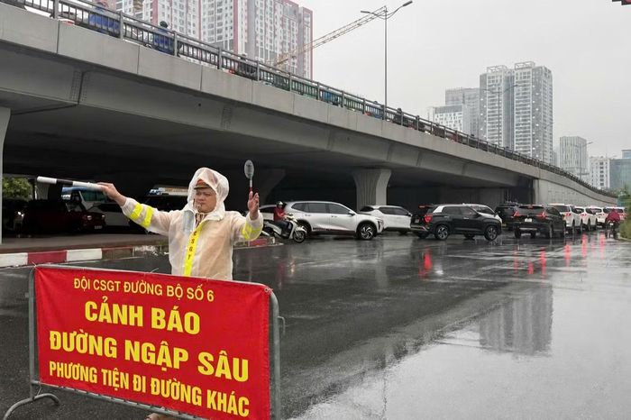 Đội CSGT đường bộ số 6 đặt biển cảnh báo, hướng dẫn phương tiện di chuyển qua khu vực nước ngập.