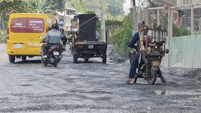  Người đi xe máy thường xuyên bị sụp ổ gà mất thăng bằng. Ảnh: Khoa Nam. 