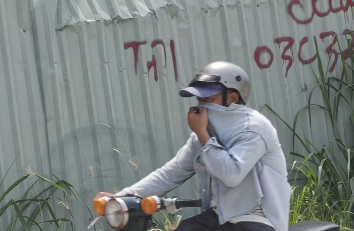  Người đi đường phải bịt mũi để tránh bụi mỗi khi chạy trên đường. Ảnh: Khoa Nam. 
