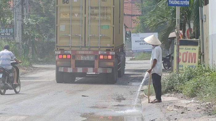 Người dân sinh sống, buôn bán trên tuyến đường Nguyễn Xiển buộc phải xịt nước để giảm bụi, chấp nhận sống chung mỗi ngày. Ảnh: Khoa Nam. 