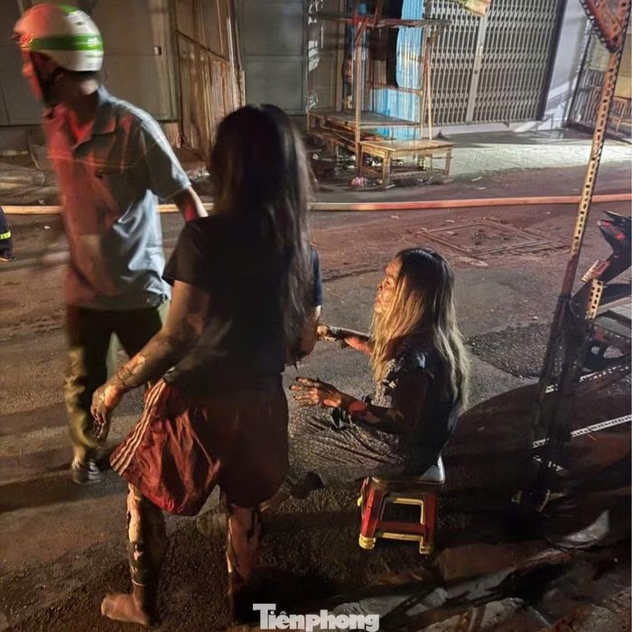 Hai mẹ con được người dân hỗ trợ đưa xuống đất sau khi nhảy từ sân thượng sang mái nhà bên cạnh. Ảnh: Nguyễn Tiến