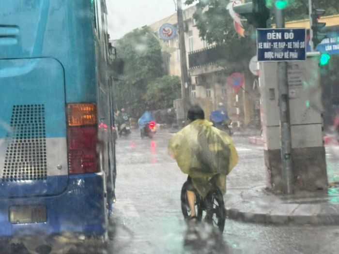 Học sinh đạp xe về trong mưa, đường ngập