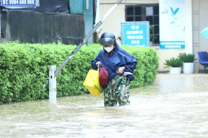 Nước lũ trên tuyến đường dẫn vào Trung tâm Y tế Hoàng Mai có nơi ngập sâu 70-90 cm, khiến việc đi lại gặp nhiều khó khăn. Người dân đến khám, cấp cứu phải tìm cách vượt qua dòng nước để tiếp cận cơ sở y tế.