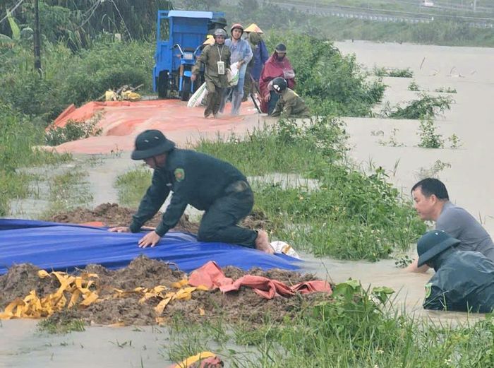 Nước tràn qua bờ kênh, lực lượng chức năng liên tục phải gia cố. Ảnh: CTV