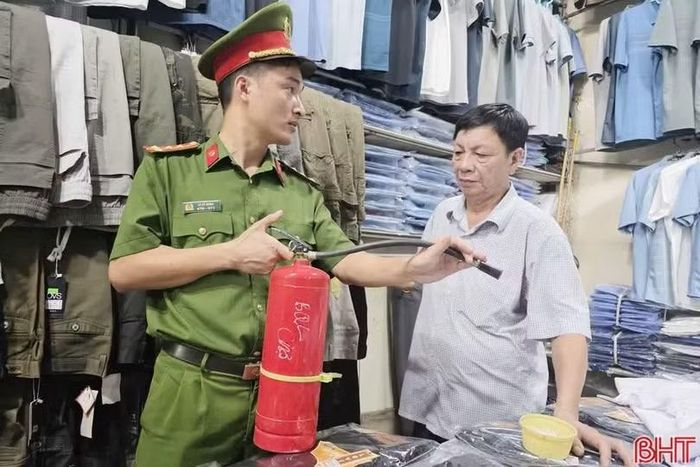 Công an xã Can Lộc hướng dẫn cách sử dụng bình chữa cháy mini cho hộ kinh doanh mặt hàng quần áo ở chợ Nghèn.