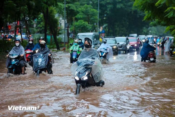 Người dân di chuyển qua đoạn 'phố biến thành sông' đầu giờ sáng nay. (Ảnh: Hoài Nam/Vietnam+)