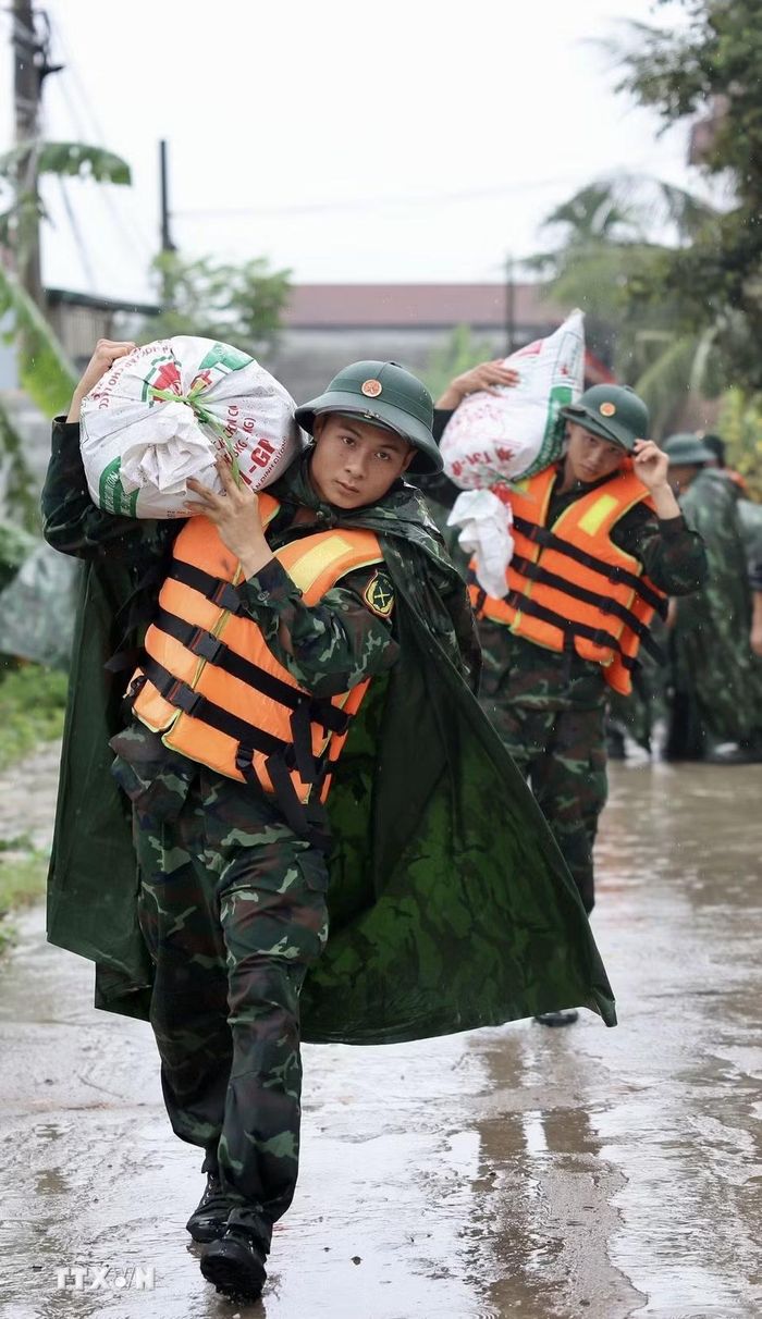 Lực lượng bộ đội hỗ trợ đắp đê bao ngăn nước khu dân cư ven sông Bùi. (Ảnh: Nhật Anh/TTXVN)