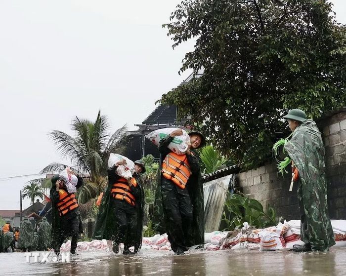 Lực lượng bộ đội hỗ trợ đắp đê bao ngăn nước khu dân cư ven sông Bùi. (Ảnh: Nhật Anh/TTXVN)