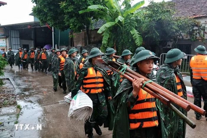 Cán bộ, chiến sỹ Trung đoàn 102, Sư đoàn 308 mang theo bao vật liệu, chuẩn bị đắp đê ngăn nước lũ tại xã Quảng Bị. (Ảnh: Phạm Tuấn Anh/TTXVN)