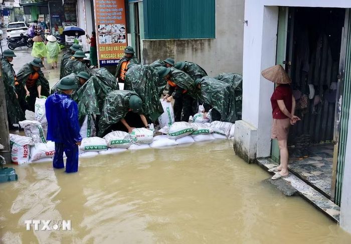 Lực lượng bộ đội hỗ trợ đắp đê bao ngăn nước khu dân cư ven sông Bùi. (Ảnh: Nhật Anh/TTXVN)