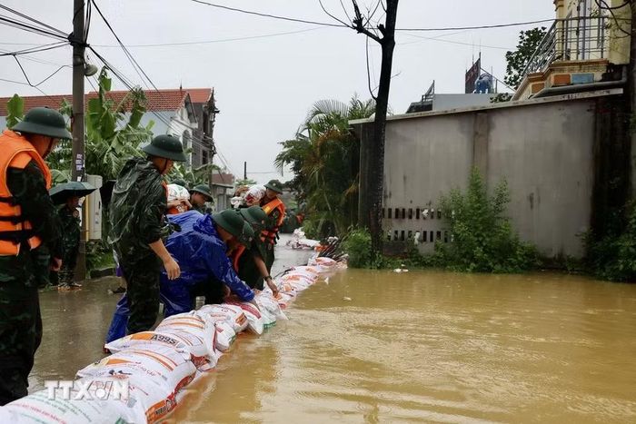 Lực lượng bộ đội hỗ trợ đắp đê bao ngăn nước khu dân cư ven sông Bùi. (Ảnh: Nhật Anh/TTXVN)