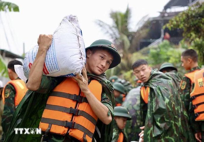 Lực lượng bộ đội hỗ trợ đắp đê bao ngăn nước khu dân cư ven sông Bùi. (Ảnh: Nhật Anh/TTXVN)