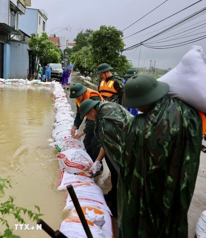 Lực lượng bộ đội hỗ trợ đắp đê bao ngăn nước khu dân cư ven sông Bùi. (Ảnh: Nhật Anh/TTXVN)