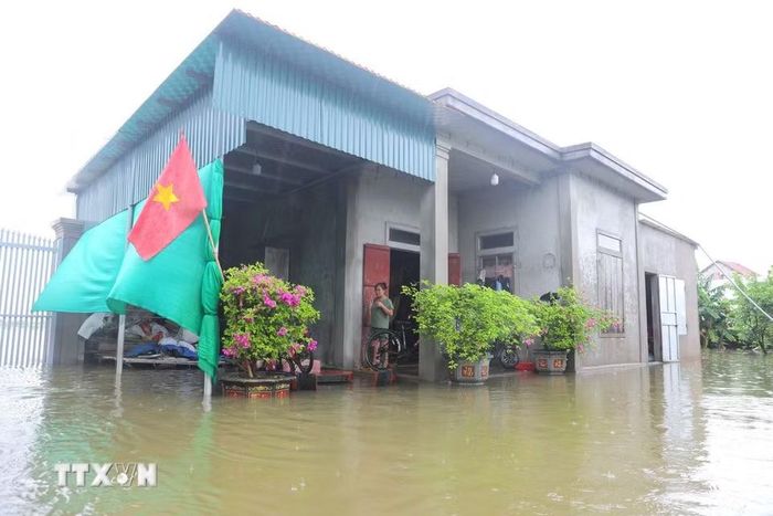 Nước lũ dâng cao, tràn vào sân và gây cô lập tạm thời nhiều nhà dân tại thôn 1, xã Quỳnh Lưu, tỉnh Nghệ An. (Ảnh: Xuân Tiến/TTXVN)