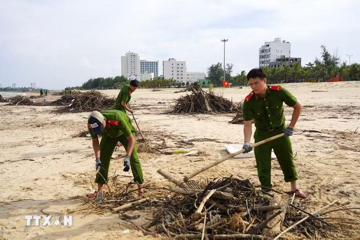 Lực lượng chức năng khẩn trương dọn rác, làm sạch bãi biển Nhật Lệ sau mưa lũ. (Ảnh: Thanh Thuỷ/TTXVN)
