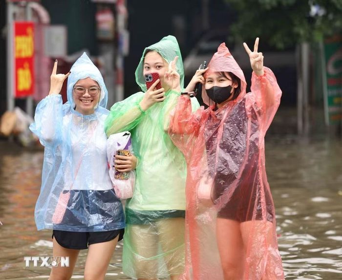 Dù phải lội nước để về nhà song người dân vẫn lạc quan, mong nước rút sớm. (Ảnh: Thanh Tùng/TTXVN)