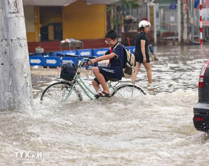 Học sinh đi học về qua đường Tây Mỗ đang bị ngập. (Ảnh: Thanh Tùng/TTXVN)