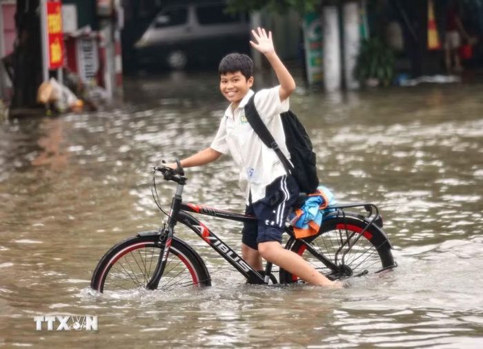Học sinh trở về nhà phải đi vào đường Tây Mỗ đang bị ngập. (Ảnh: Thanh Tùng/TTXVN)