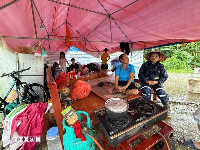 Mưa, rét, khó khăn đủ bề nhưng gia đình bà Vũ Thị Chừ, 72 tuổi, xã Kim Tân vẫn động viên nhau cùng cố gắng, đợi nước rút sẽ về dọn dẹp nhà cửa. (Ảnh: Hoa Mai/TTXVN)