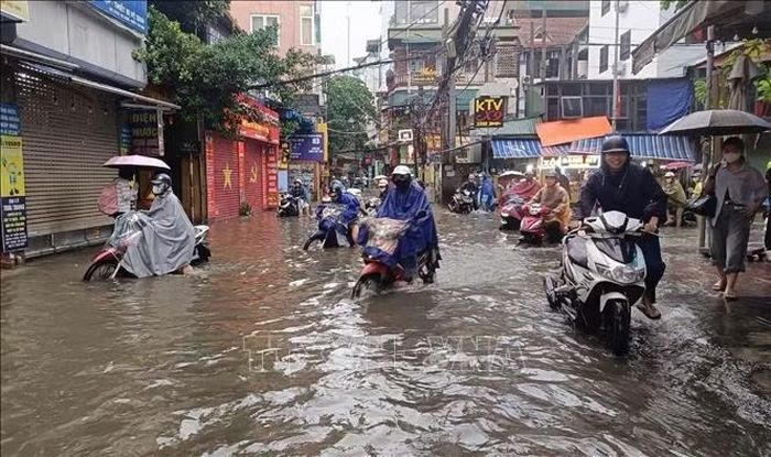 Người dân phải dắt xe qua các điểm ngập trên phố Triều Khúc. Ảnh: Nguyễn Thắng/TTXVN