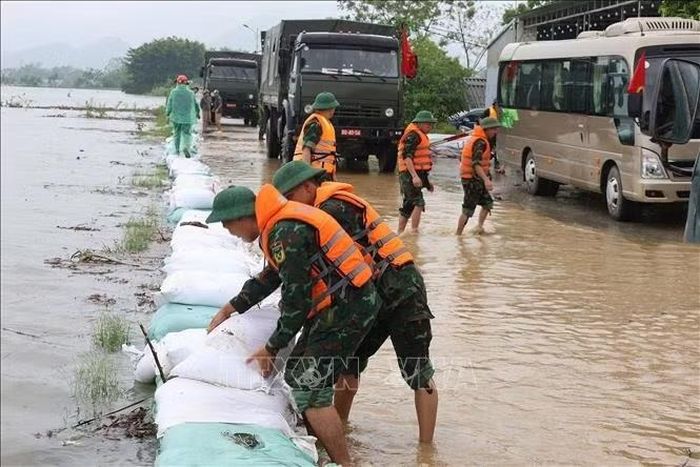 Xếp bao cát dọc mép đê, phủ bạt nhằm hạn chế dòng nước xối mạnh làm hỏng mặt và mái đê. Ảnh: Nguyễn Cúc/TTXVN