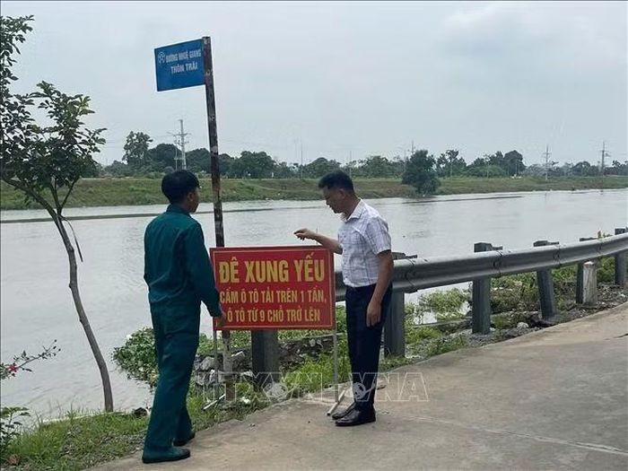 Lực lượng chức năng xã Chuyên Mỹ đặt biển cảnh báo hạn chế phương tiện tại vị trí xung yếu trên tuyến đê sông Nhuệ qua địa bàn. Ảnh tư liệu: TTXVN phát