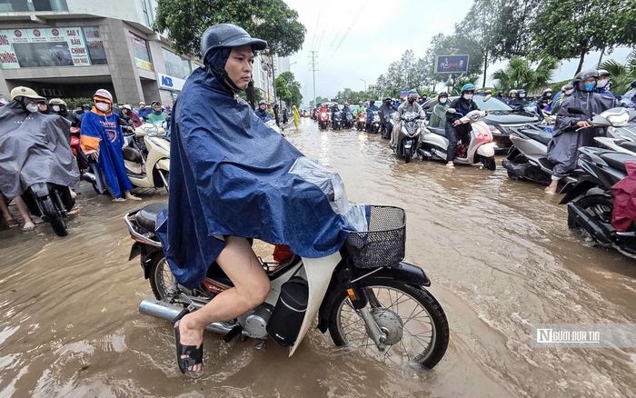Ô tô, xe máy vất vả đi qua tuyến đường ngập dưới cơn mưa nặng hạt.