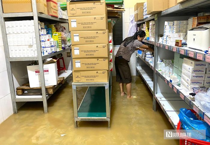 Nước tràn vào kho, các nhân viên y tế đưa vật tư lên cao và phải lội nước lấy thuốc phục vụ người bệnh.