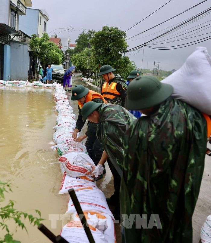 Lực lượng bộ đội hỗ trợ đắp đê bao ngăn nước khu dân cư ven sông Bùi. Ảnh: Nhật Anh - TTXVN 