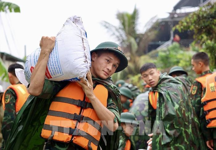 Lực lượng bộ đội hỗ trợ đắp đê bao ngăn nước khu dân cư ven sông Bùi. Ảnh: Nhật Anh - TTXVN