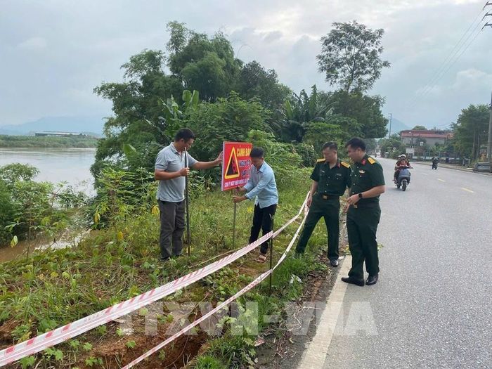 Lực lượng chức năng các địa phương cắm biển cảnh báo nguy cơ sạt lở, ngập. Ảnh: TTXVN phát