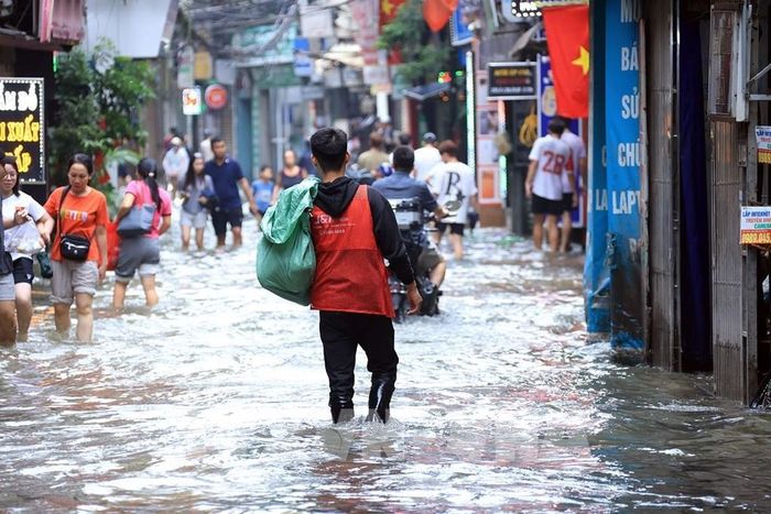 Một shipper gặp khó khăn khi đi giao hàng. Ảnh: Tuấn Anh - TTXVN 