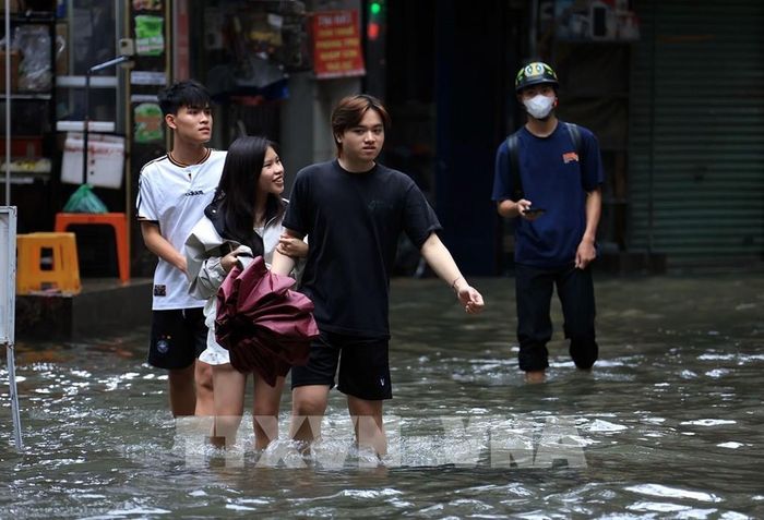 Người dân đi lại khó khăn do nước ngập sâu trên phố Triều Khúc. Ảnh: Tuấn Anh - TTXVN