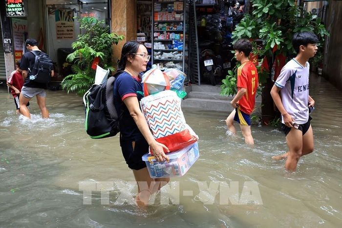 Người dân di chuyển đồ đạc đến nơi khô ráo. Ảnh: Tuấn Anh - TTXVN 