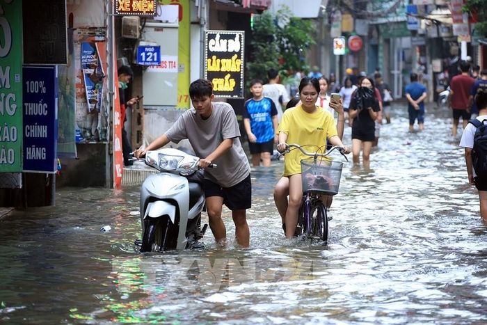 Người dân gặp khó khăn khi đi qua điểm ngập nước. Ảnh: Tuấn Anh - TTXVN