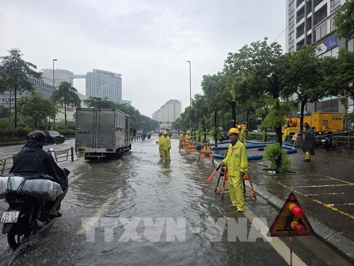 Khẩn trương tiêu thoát nước trên đường Võ Chí Công. Ảnh: Nguyễn Thắng - TTXVN