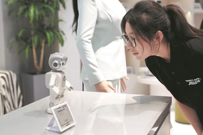 Một nhân viên tương tác với robot đồng hành tại nhà ở Robot Mall, cửa hàng 4S đầu tiên trên thế giới chuyên về robot thông minh có khả năng tương tác và hoạt động trong môi trường thực