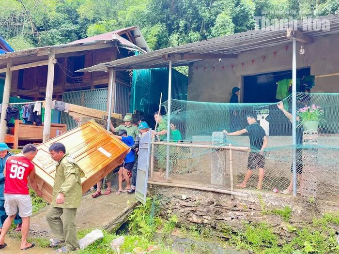 Lực lượng chức năng và người dân hỗ trợ di chuyển tài sản của hộ dân nằm trong khu vực có nguy cơ mất an toàn do sạt lở.