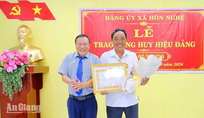 Bí thư Đảng ủy xã Hòn Nghệ Tạ Minh Tài trao Huy hiệu 35 năm tuổi Đảng cho ông Nguyễn Công Trãi. Ảnh: DANH THÀNH
