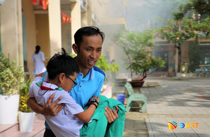 Một giáo viên hỗ trợ học sinh rời khỏi khu vực có đám cháy. Ảnh: ALĂNG NGƯỚC
