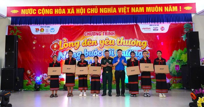 Tặng máy tính xách tay cho học sinh vượt khó học giỏi. Ảnh: ĐVCC